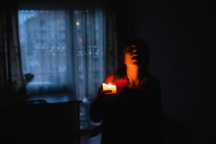 Woman with candle at home because of power cut