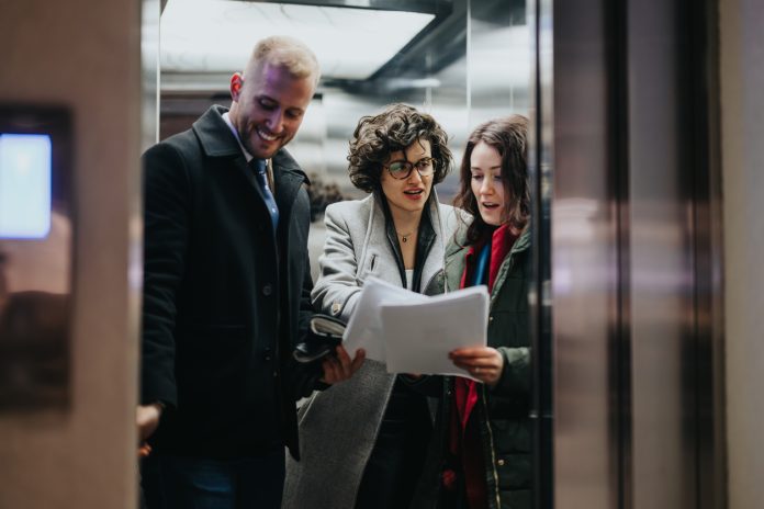 People reviewing documents together in modern office elevator.